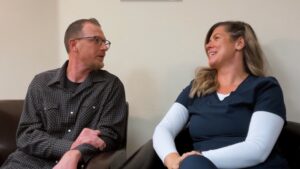 Two people sitting on a couch, smiling and engaging in conversation.