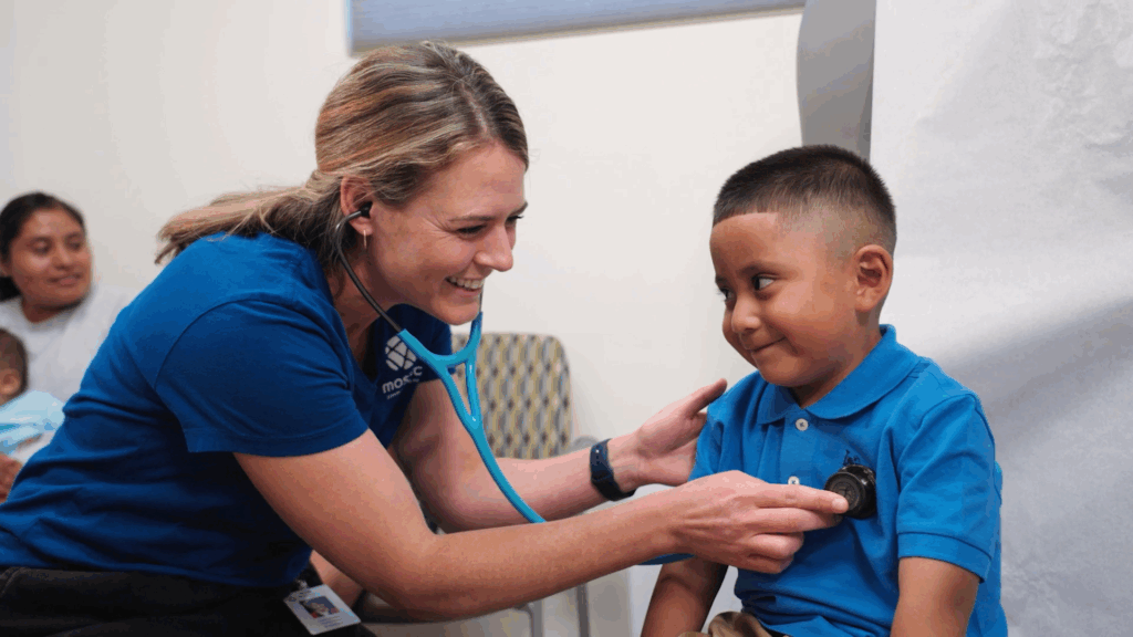 A healthcare professional using a stethoscope on a young boy in a medical setting.
